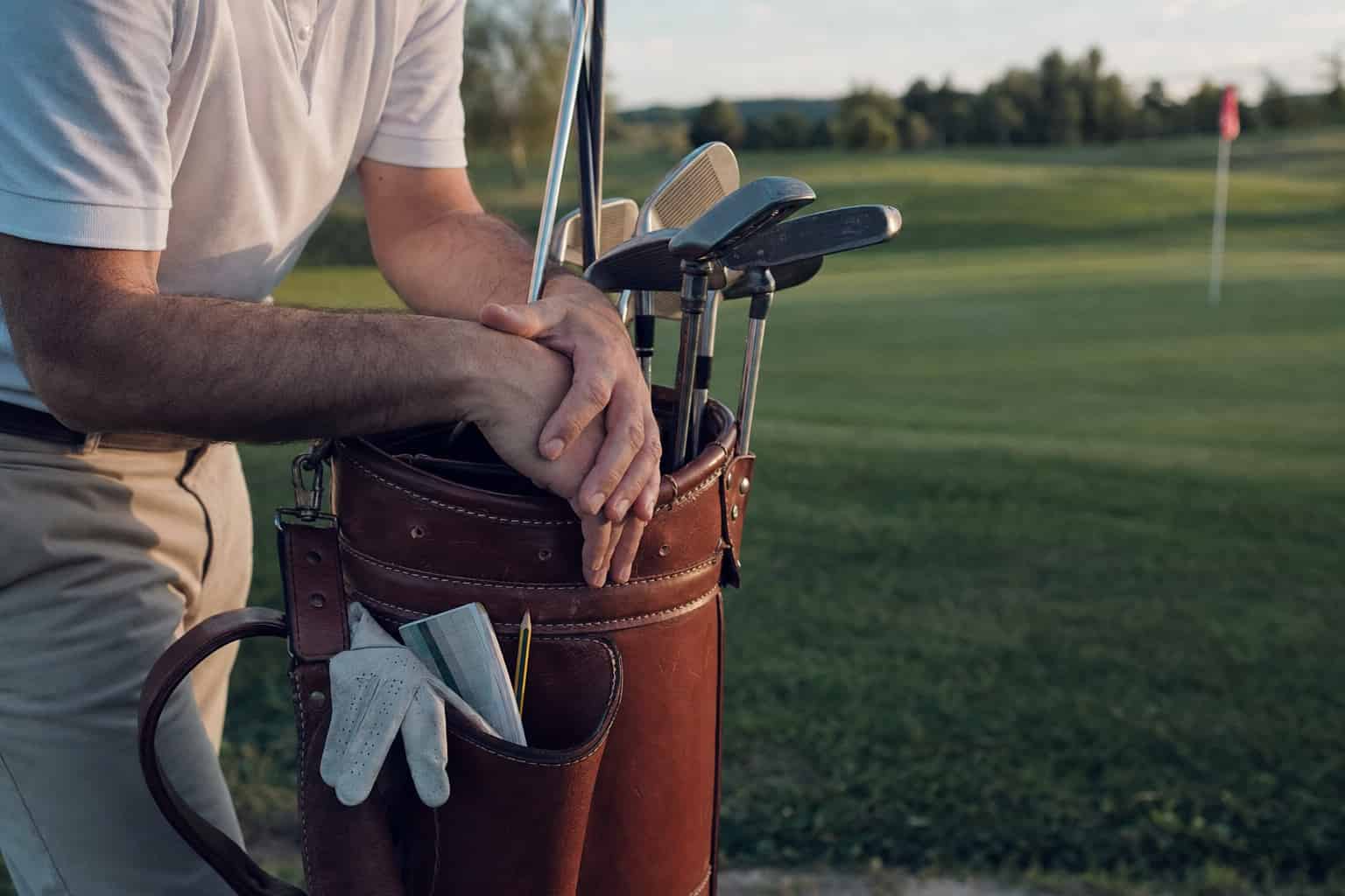 Golfspieler stützt sich auf sein Golfbag am Rand des Fairways